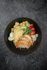 Salad with roasted chicken breast sliced in layers, quail egg, cherry tomatoes and grated parmesan cheese