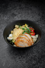 Salad with roasted chicken breast sliced in layers, quail egg, cherry tomatoes and grated parmesan cheese