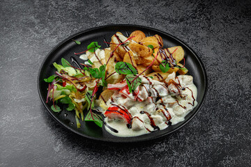 Baked potato slices with stewed vegetables in a cream sauce in a dark plate