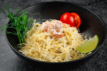 Pasta carbonara with shrimp in dark plate