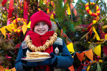 smiling boy going to eat pancakes  at the traditional Russian festival dedicated to the meeting of spring, the week of pancakes, Shrovetide. decorations for the Maslenitsa holiday