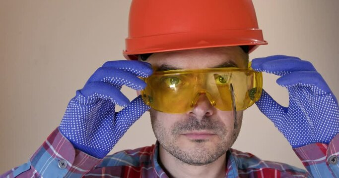 Worker in helmet removes goggles with part of stuck saw disk. During working process part of saw blade became lodged in safety glasses closeup