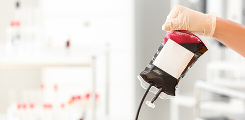 Hand of medical worker holding blood pack for transfusion in hospital