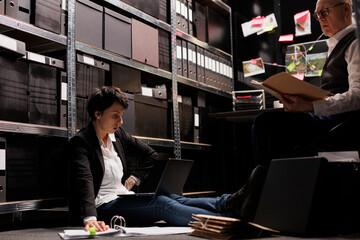 Private detective woman sitting on floor in arhive room, analyzing criminology report. Police...