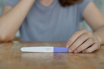Pregnancy concept. Happy young pregnant woman holding a positive pregnancy test looking excited and reading result for a baby at home. Family, motherhood, love, enjoy and smile together for happiness.