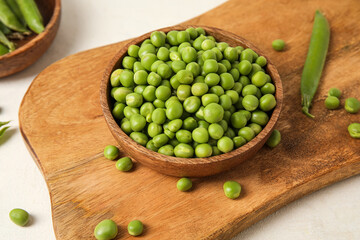 Bowl and wooden board with fresh green peas on white background, closeup