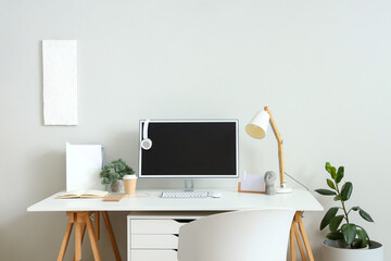 Comfortable workplace with modern computer near light wall