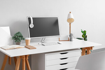 Comfortable workplace with modern computer near light wall