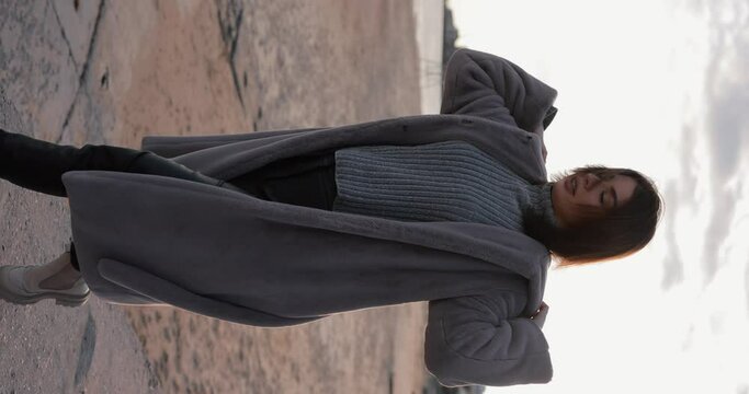 Beautiful woman in fur coat walking at the winter embankment, slow motion vertical video