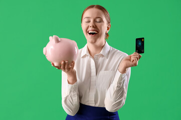 Young businesswoman with credit card and piggy bank on green background