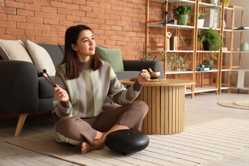 Young woman with sticks playing glucophone at home