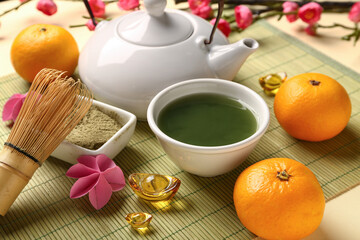 Teapot with matcha tea, mandarins and sakura on light background. Japanese New Year celebration