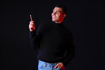 Young man with electronic cigarette on black background