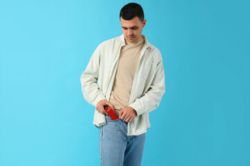 Young man with electronic cigarette on blue background