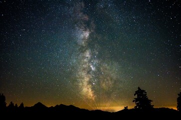Milky Way over the Chiemgau Alps with the Sonntagshorn, the rays on the horizon seem to come from a light show or laser show near Kitzbuehel, Inzell, Bavaria, Germany, Europe