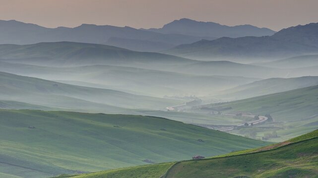 Morning mist, back-to-back hill ranges, green fields, haze, individual houses, Madonie National Park, spring, Sicily, Italy, Europe