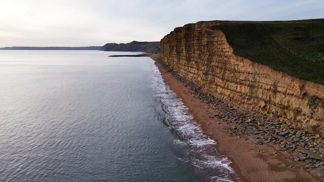 Top cinematic aerial view to the West Bay Cliffs, West Bay, Jurassic Coast, Dorset, England. 4K drone footage.