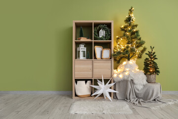 Wooden shelving unit, Christmas trees and decorations near green wall