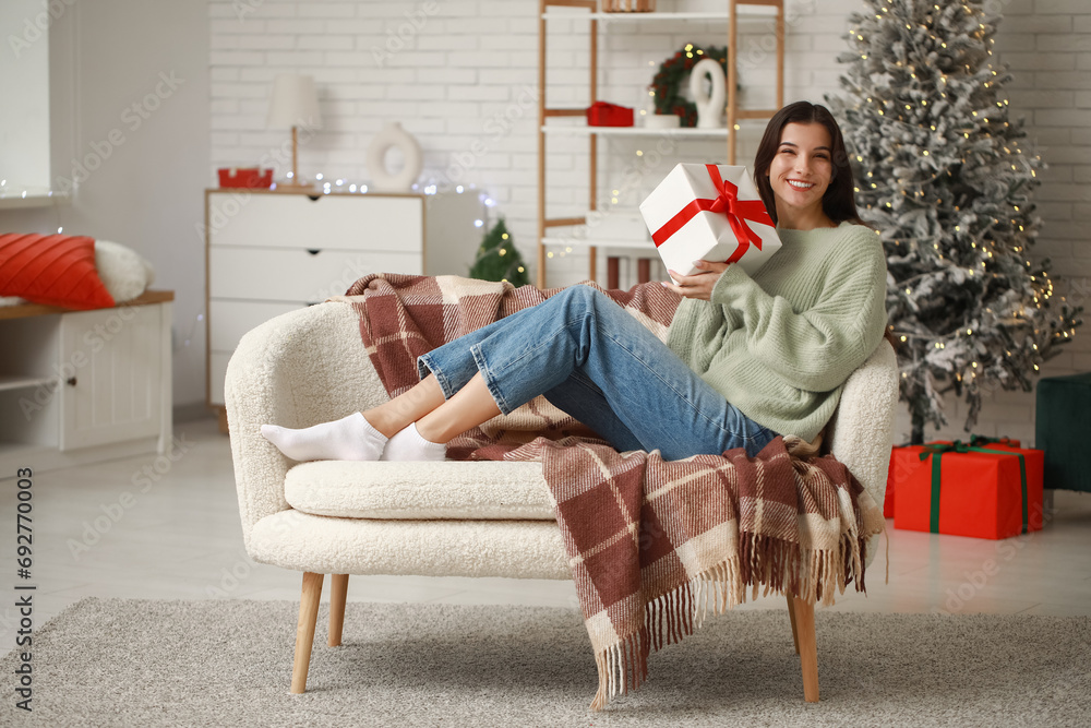 Poster Beautiful young woman with gift at home on Christmas eve