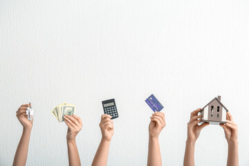 Female hands with house figure, keys, money and credit card on light background. Concept of buying...