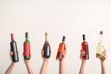 Female hands with bottles of wine and champagne on light background