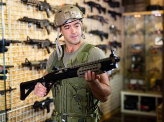 Positive man in army uniform with weapon in military market