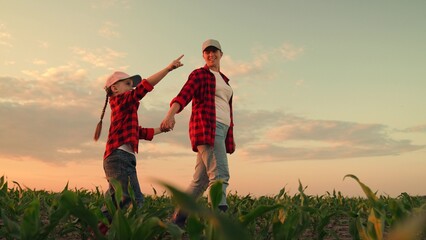 Happy farmers, mom, daughter go field, holding hands. Child, kid points to sunset. Little girl,...