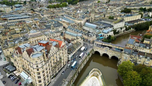 Top cinematic aerial view to the Georgian City of Bath and Bath Cathedral, Somerset, England. Pulteney Bridge and Weir on the river Avon, Bath, Somerset, England.