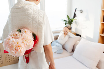 Beautiful woman sitting at home in bedroom man holding beautiful bouquet of flowers, selective focus