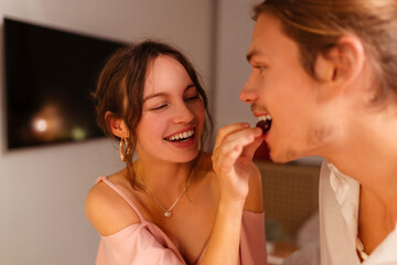 Happy, couple in love eating, woman feeding her boyfriend, romantic date in restaurant