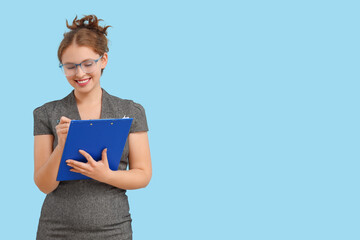 Young businesswoman in eyeglasses with clipboard on blue background