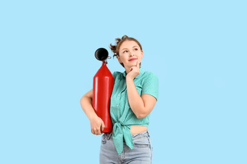 Thoughtful young woman with fire extinguisher on blue background