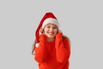 Young woman in Santa hat on light background