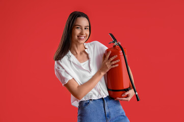 Young woman with fire extinguisher on red background