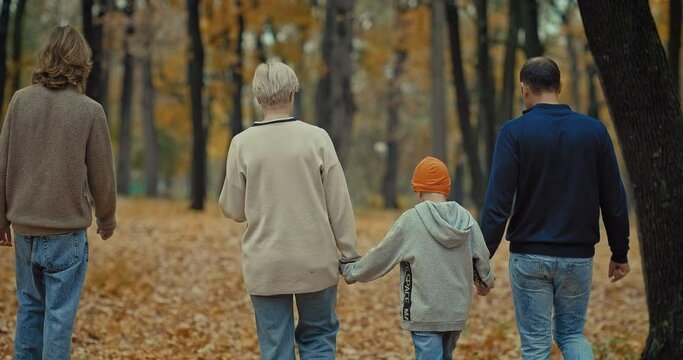 happy dad and mom walking with children in beautiful park in autumn, back view, 4K, Prores