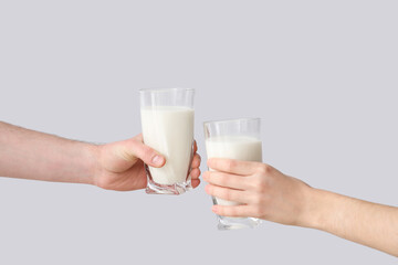 Hands with glasses of milk on grey background