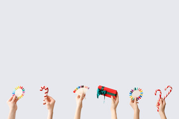 Hands holding colorful press-on nails and Christmas decorations on white background