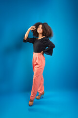 Beautiful young woman, standing, in casual clothes, touching her black power hair.