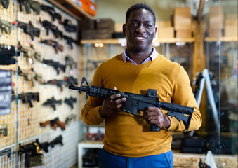 Customer man is choosing air-powered gun in army market