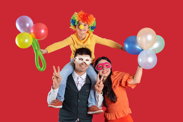 Obraz na płótnie Canvas Happy family in costumes and carnival masks with balloons on red background