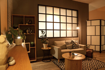 Interior of modern living room with grey sofa, coffee table, wooden cabinet and glowing lamps at...