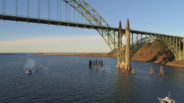 Aerial Drone Video- Yaquina Bay Bridge Sunrise- Newport Oregon-  North support detail- dolly out w boat approaching V-12