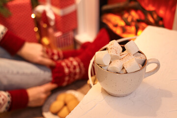 Fototapeta na wymiar Cup of hot chocolate with marshmallows on table in festive living room, closeup