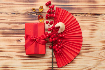 Gift box with fortune cookie and Chinese symbols on wooden background. New Year celebration