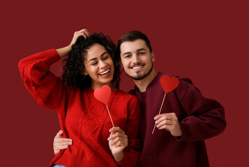 Young couple with paper hearts for Valentine's day on red background