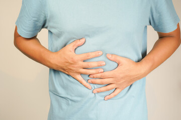 male having stomach ache, bending over and holding hands on stomach, uncomfortable due to stomach...