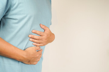 male having stomach ache, bending over and holding hands on stomach, uncomfortable due to stomach...