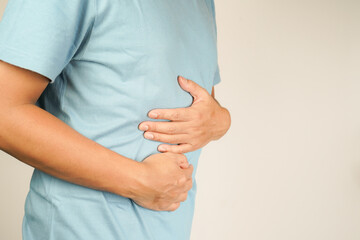 male having stomach ache, bending over and holding hands on stomach, uncomfortable due to stomach...