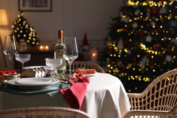 Christmas table setting with bottle of wine, appetizers and dishware indoors