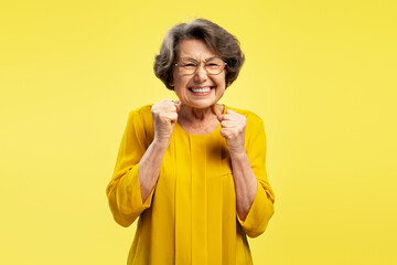 Funny emotional senior woman, happy modern grandmother holding hands celebration success isolated...